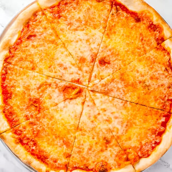 A whole Dragos Pizza cheese pizza, cut into eight slices, on a white marble surface.
