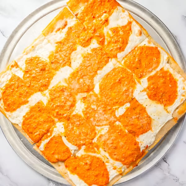 Square Sicilian pizza with white cheese and orange sauce on a metal tray.